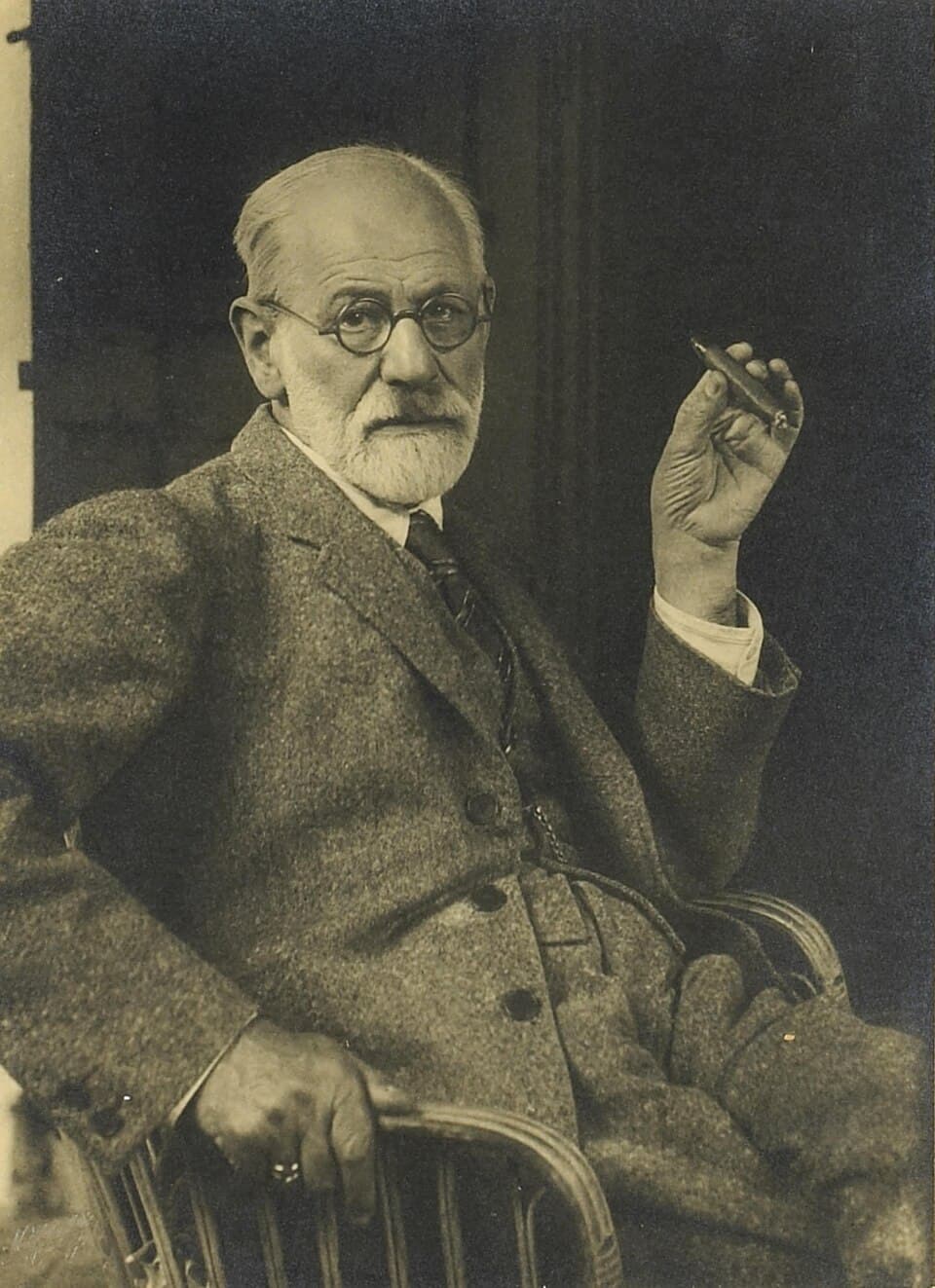 Photographic portrait of Sigmund Freud seated, with a short beard and a cigar.